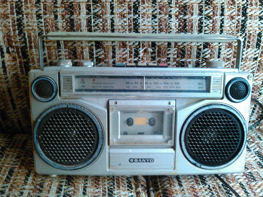 An old boombox from the 80s on a couch.